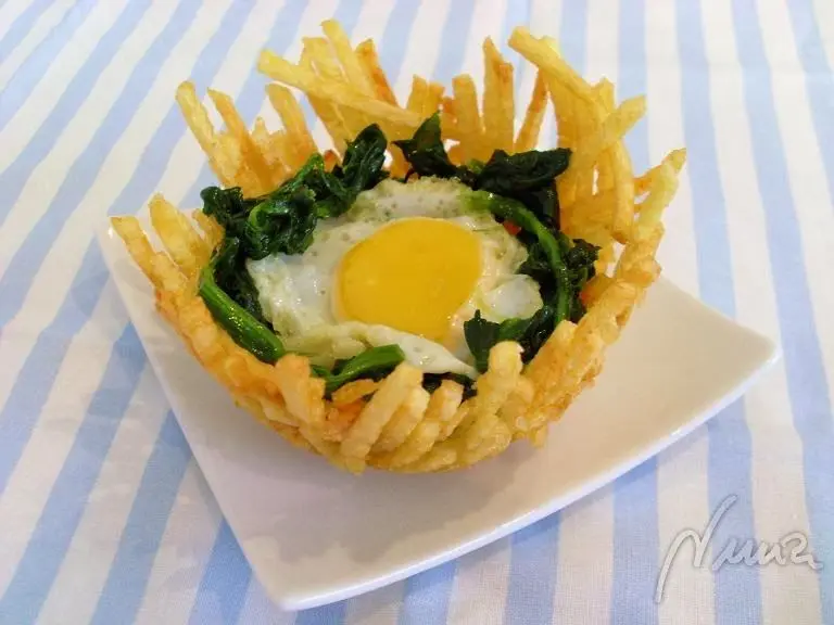 Huevo en nido, paso 13: colocar los huevos fritos de codorniz encima del lecho de espinacas.