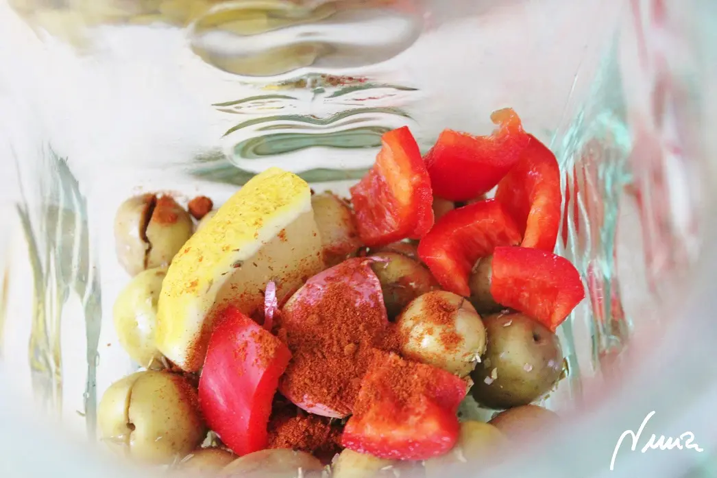 Aceitunas verdes aliñadas, paso 3: Echar en el tarro de cristal los trocitos de pimiento rojo, los trozos de limón y los ajos