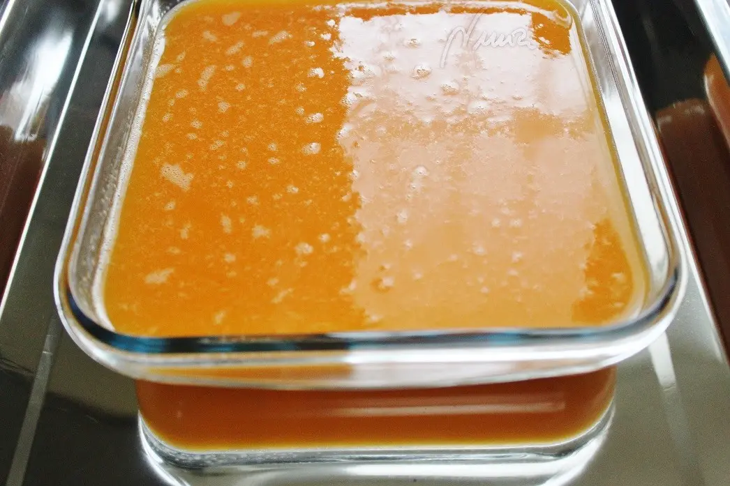 Tocino de cielo, paso 4: Poner el colador sobre la fuente cuadrada y colar la mezcla de yemas con almíbar sobre…